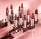 Batons Natura Una abertos em tons nude e rosados sobre fundo rosa reflexivo.