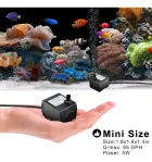Bomba submersa preta miniatura na mão, com aquário de peixes coloridos.