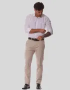 Calça de sarja masculina bege em homem com camisa branca, cinto preto, enrolando manga.