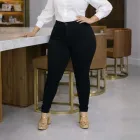 Mulher em pé com calça jeans plus size preta cintura alta