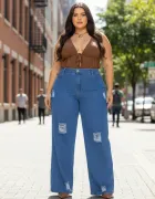 Calça jeans azul wide leg rasgada em modelo plus size com blusa marrom.