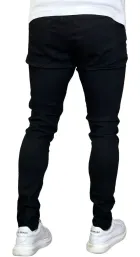Calça Skinny Preta Masculina, vista traseira, preta, com bolsos traseiros e tênis brancos.