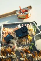 GoPro Hero 13 Black sobre iscas de pesca coloridas com vara e molinete.