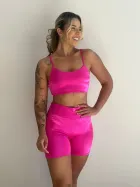 Conjunto Fitness rosa choque de top e shorts veludo, mulher sorrindo.
