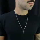 Corrente de prata masculina com pingente crucifixo em homem de camiseta preta.
