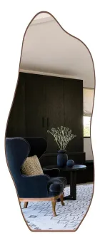 Espelho Orgânico corpo inteiro com moldura caramelo, refletindo poltrona azul.