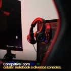 Headset gamer preto com RGB LED pendurado no PC.