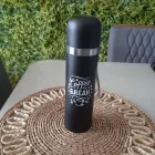 Garrafa térmica preta com estampa Coffee Break, anel prateado, sobre sousplat de palha.