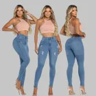 Mulher com calça jeans feminina skinny azul clara rasgada e top pêssego