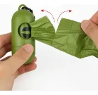 Mãos puxando saco de lixo pet verde de dispenser verde.