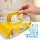 Mão abrindo pacote amarelo de lenços umedecidos Upa Bebê com tampa flip-top.