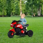 Criança com mini moto elétrica triciclo vermelha em gramado