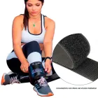 Mulher ajusta caneleira preta com logo azul e fecho de velcro