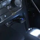 Adaptador Carplay mini preto com luz azul conectado ao USB do carro.