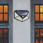 Luminária solar preta com painel e LEDs brancos em parede cinza