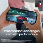 Mãos seguram smartphone Galaxy A05s preto exibindo jogo de corrida.